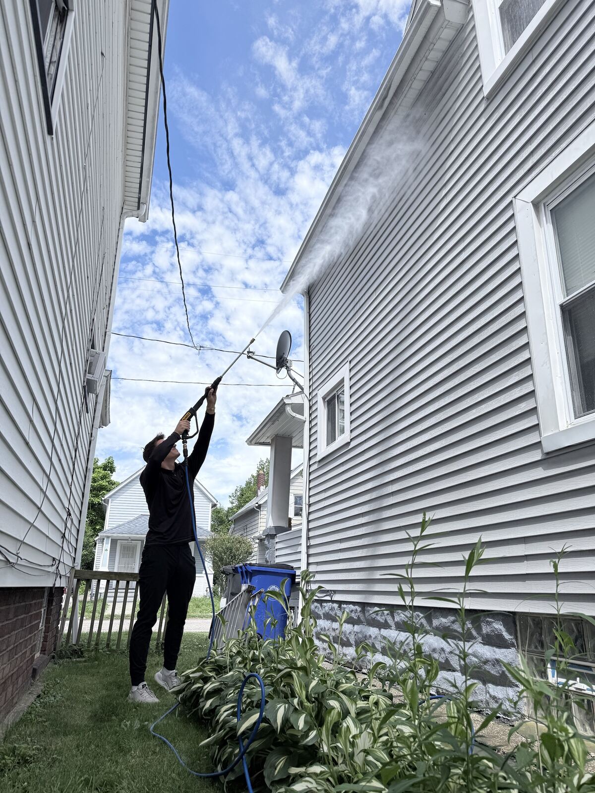 Soft-washing a roofline from a ladder